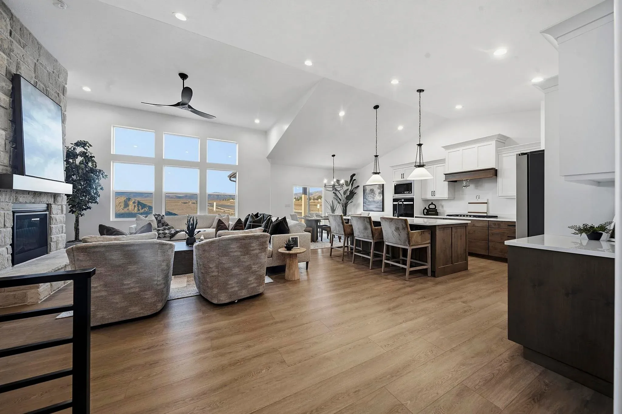 An Eagle Point Homes living room and kitchen with large windows and a stone fireplace