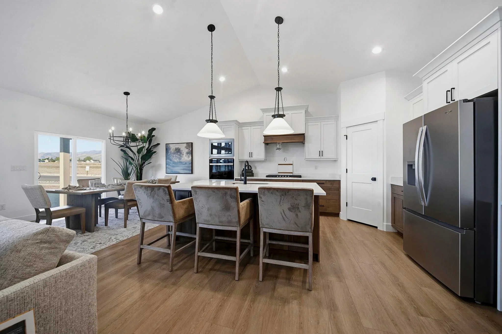 An Eagle Point Homes kitchen with a broad island, pendant lighting, and dark refrigerator