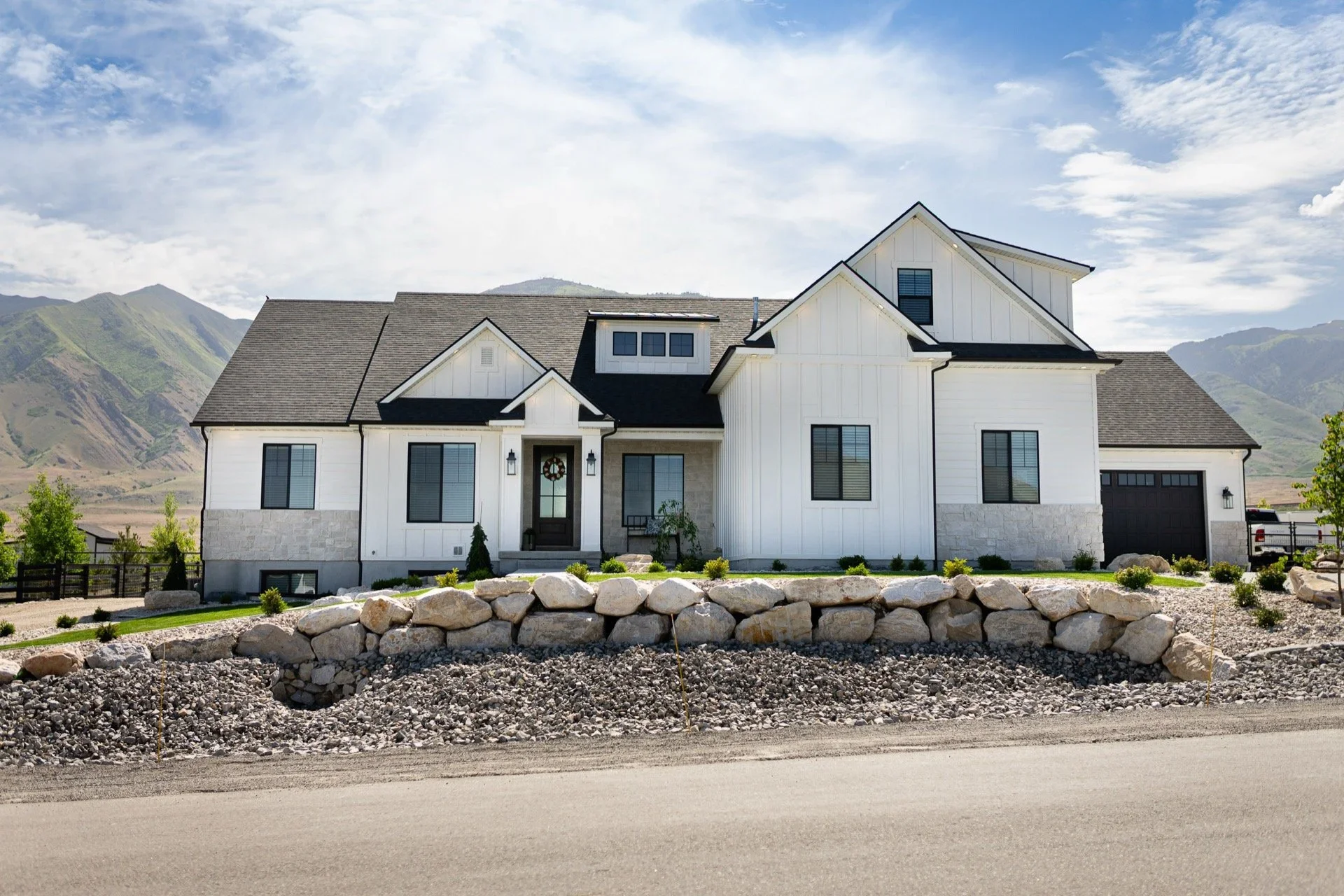 An Eagle Point Homes example with a covered porch, stone landscaping, and Utah mountains behind it